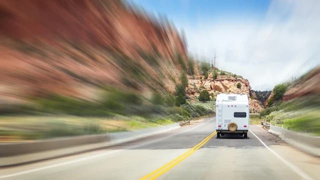 A blurry image of an RV driving down a mountain road.