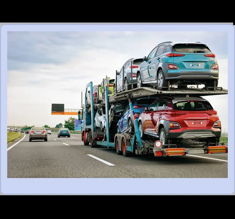 A car carrier truck transports multiple new SUVs on a highway alongside other vehicles under a cloudy sky.