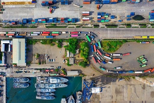 Aerial view of a shipping port with colorful containers and docked boats.