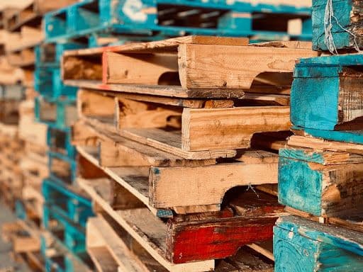 Stacked wooden pallets with blue painted ends.