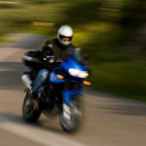 A person riding a motorcycle down a curvy road using motorcycle chocks.