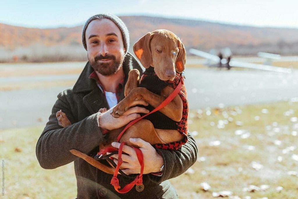 A man in a field walking with a dog.
