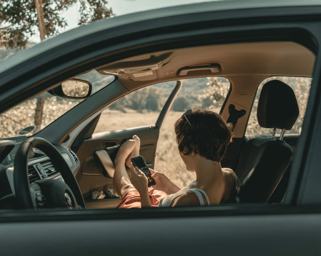 A woman engaging in customer communication from the driver's seat of a car.