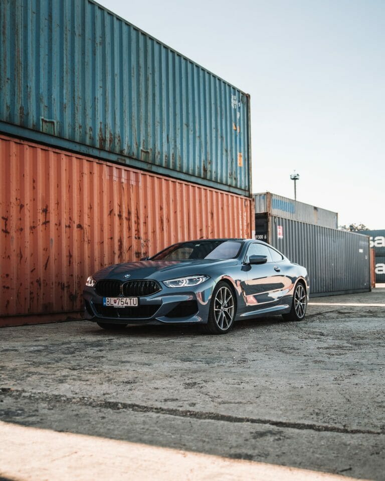 The BMW 8 series coupe parked in front of shipping containers, requesting quotes for auto transport.