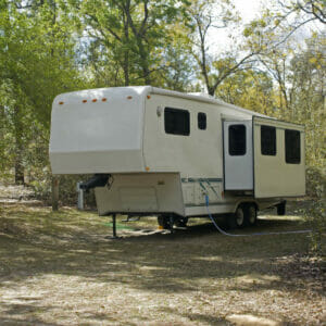 A camper parked in a wooded area.