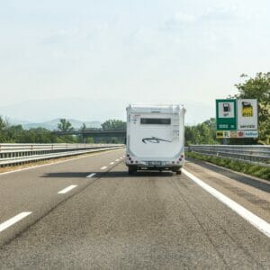 An RV delivery service transporting a vehicle on an Italian highway.