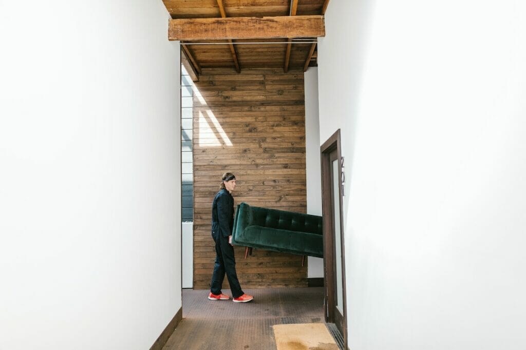 A man transporting furniture in a corridor.