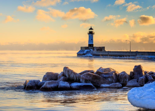 A lighthouse sits on a frozen body of water.