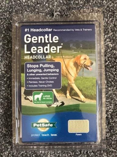 Packaging for a PetSafe Gentle Leader headcollar, large size. Featuring a joyful photo of happy dogs, including a Boxer in a park setting. This essential gear is suitable for large dogs, 60-130 lbs.