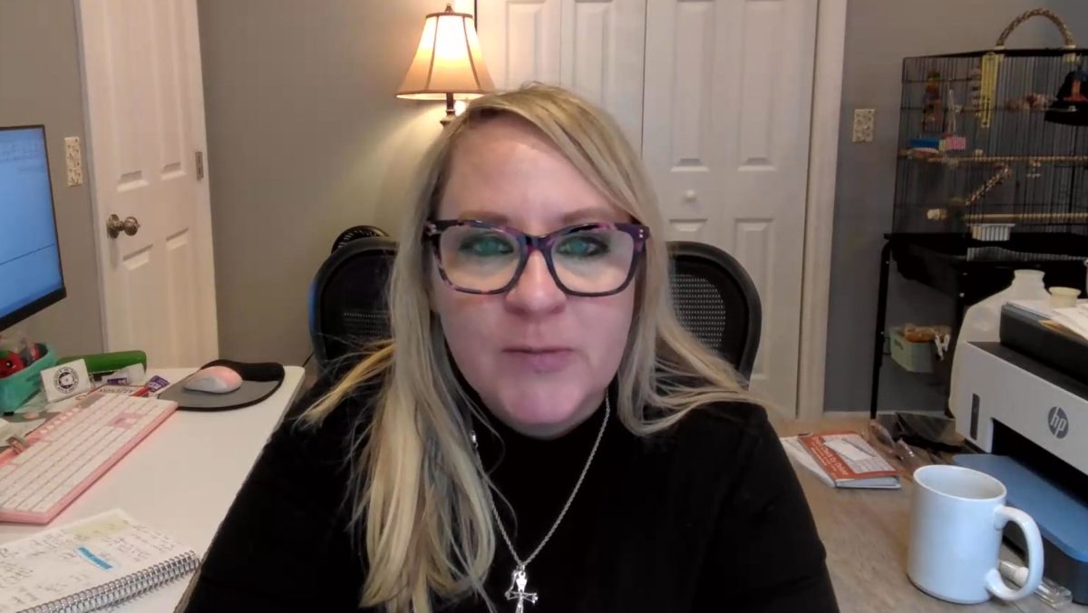 A blonde woman with glasses sits in front of a computer in a home office, coordinating a dog transport via CitizenShipper.